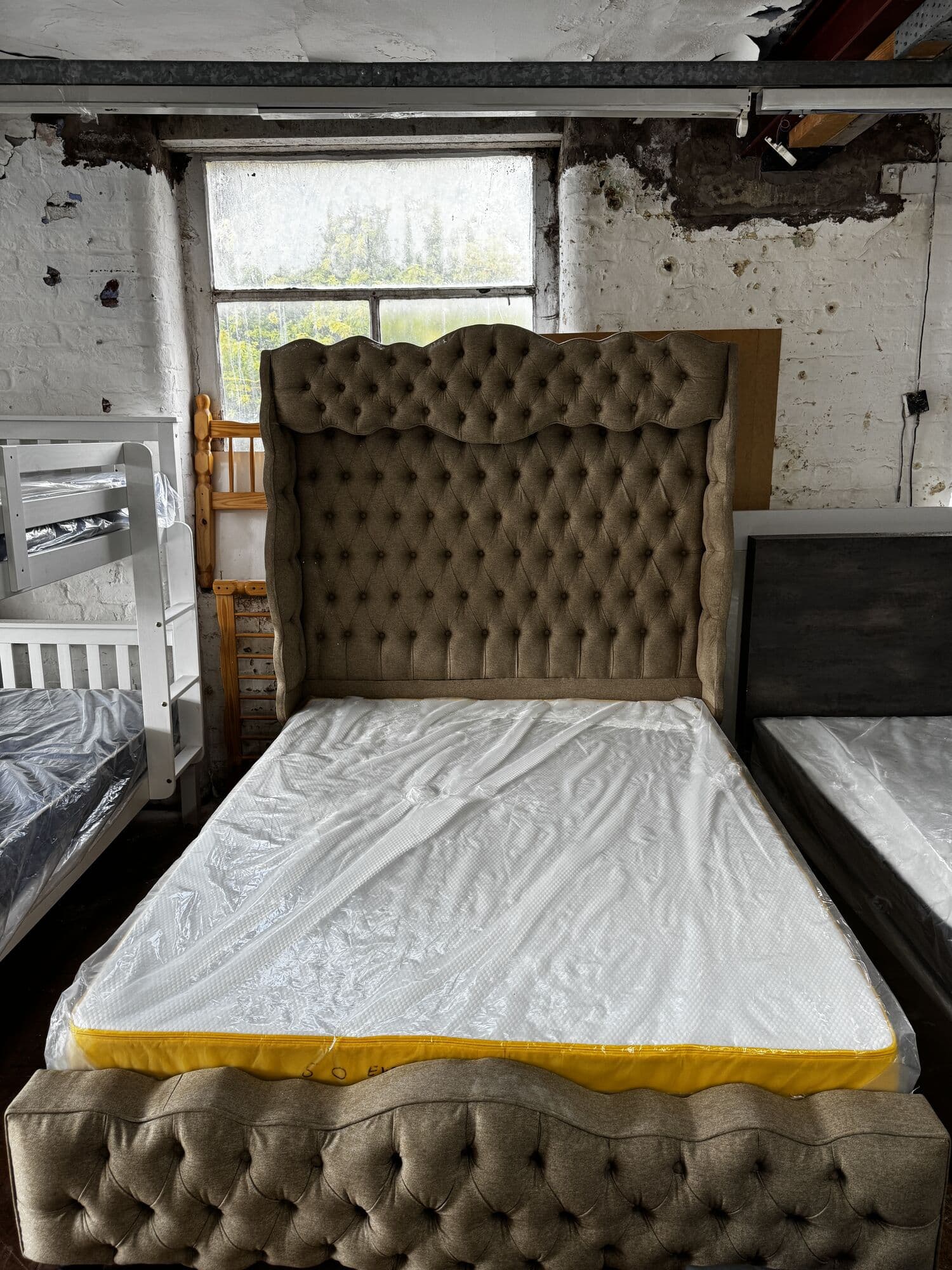 Buttoned wingback bed frame with mattress in the mill's brick room