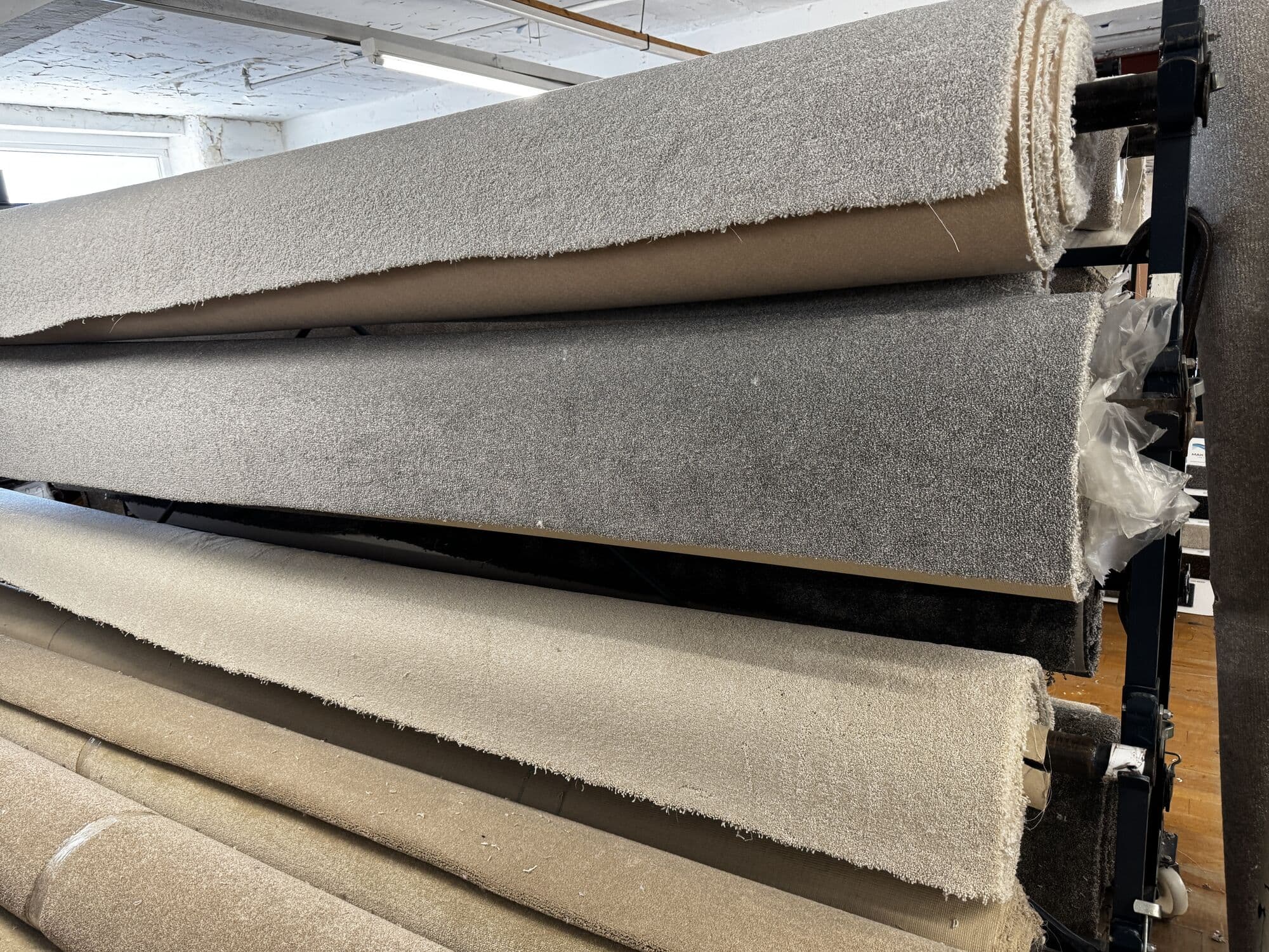 Rolls of grey and oatmeal saxony carpet on the rack