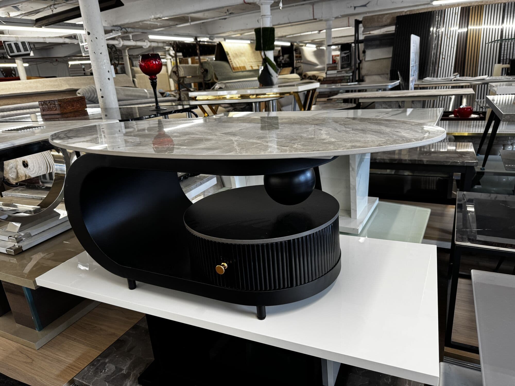 Oval marble effect coffee table with a fluted black drawer base