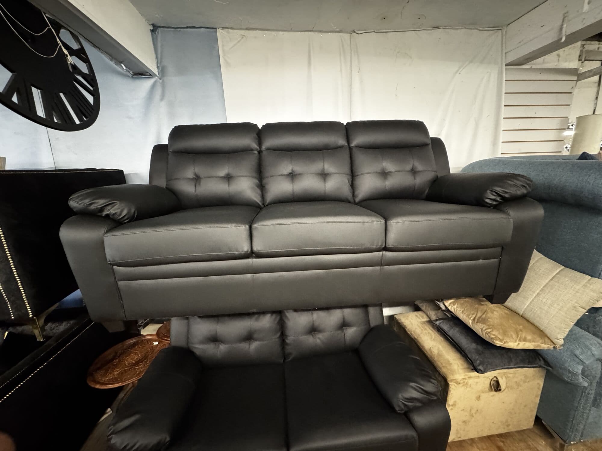 Black leather three seater sofa with tufted back cushions